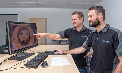 Zwei WTN-Mitarbeiter die in der Prozessvorbereitung auf einem Bildschirm ein Bauteil für den 3D Druck betrachten