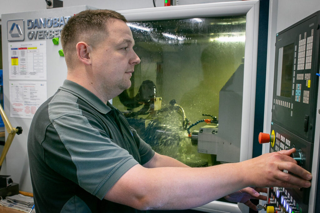 Ein Mitarbeiter von WTN vor seiner Maschine stehend bei der Arbeit, Innen-Außen-Unrundschleifen
